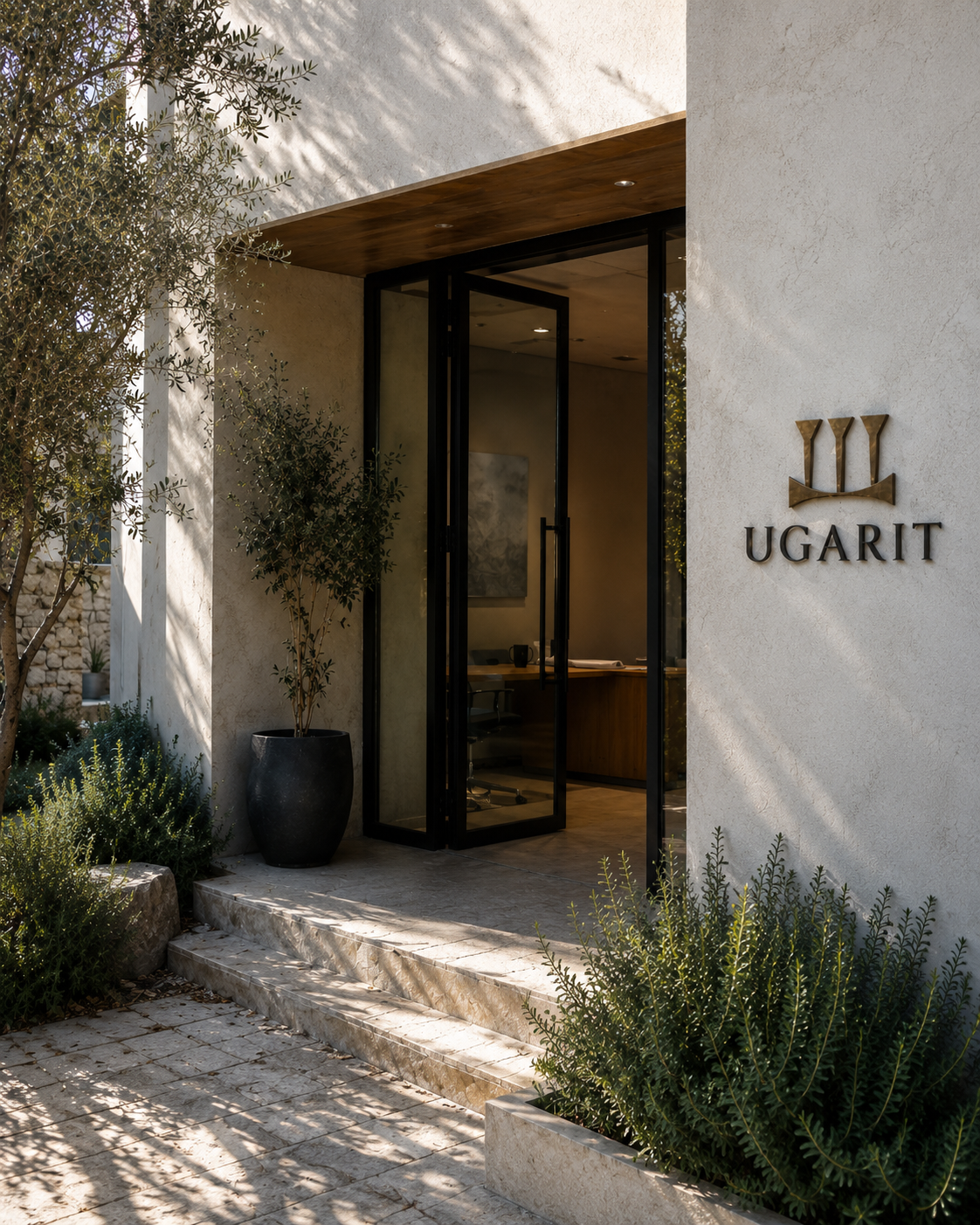 Ugarit entrance — signage on stone facade with olive tree and steel-and-glass door